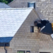Two builders are seen hanging from a digger bucket without safety equipment, in order to place a stone into the wall of a new house they are working on.