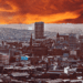 The Sheffield skyline is seen, with an artificially generated orange sky, casting the scene in contrasting hues of blue and orange.