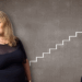 Karen Booth, Associate Partner and Head of Clinical Negligence at Pabla & Pabla, stands proudly to the left hand side of frame. Behind her, a well dressed arm carries a stick of chalk, and draws a steadily ascending staircase behind Karen.