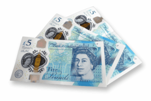 A trio of £5 notes are seen, with a light shadow cast beneath them.