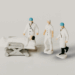 Small scale figurines of medical staff approach a hospital bed set on wheels. Atop the bed is a patient, on the precipice of facing severe medical negligence.