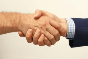 Two hands clasp each other in a firm handshake, signifying a mutually agreeable and amicable solution.