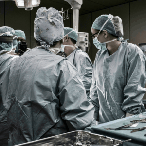 A group of surgeons dressed in PPE stand around an operating table. Their eyes are collectively fixed on their work, though they may be on the cusp of enacting medical negligence.