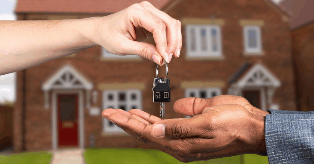 Outstretched hands eagerly anticipate the drop of some fresh new house keys. Behind the hands, a newly purchased home is seen. Overlaid is white text, reading; Conveyancing Solicitors - Based in West Didsbury, Manchester.