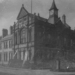 An archive photograph of the Old Town Hall, West Didsbury, is seen in scratched black and white.